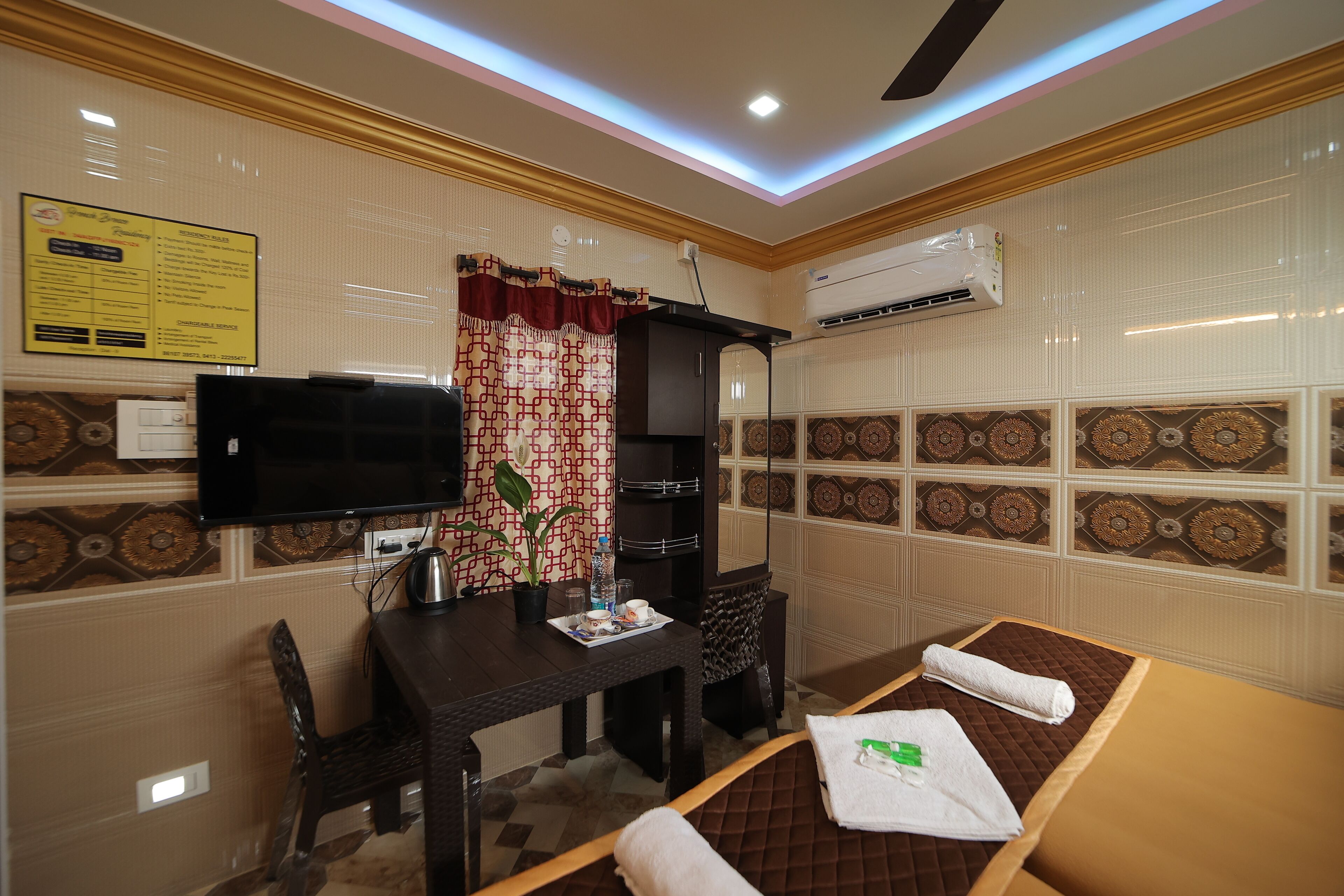 A hotel room with a bed, a desk, a television, and a wall-mounted air conditioner.