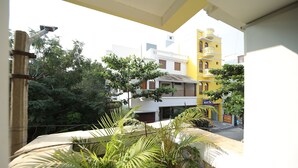 Un balcón con plantas en macetas, vista de un edificio amarillo con un letrero que dice 'Martinez's' y 'Habitaciones en alquiler'.