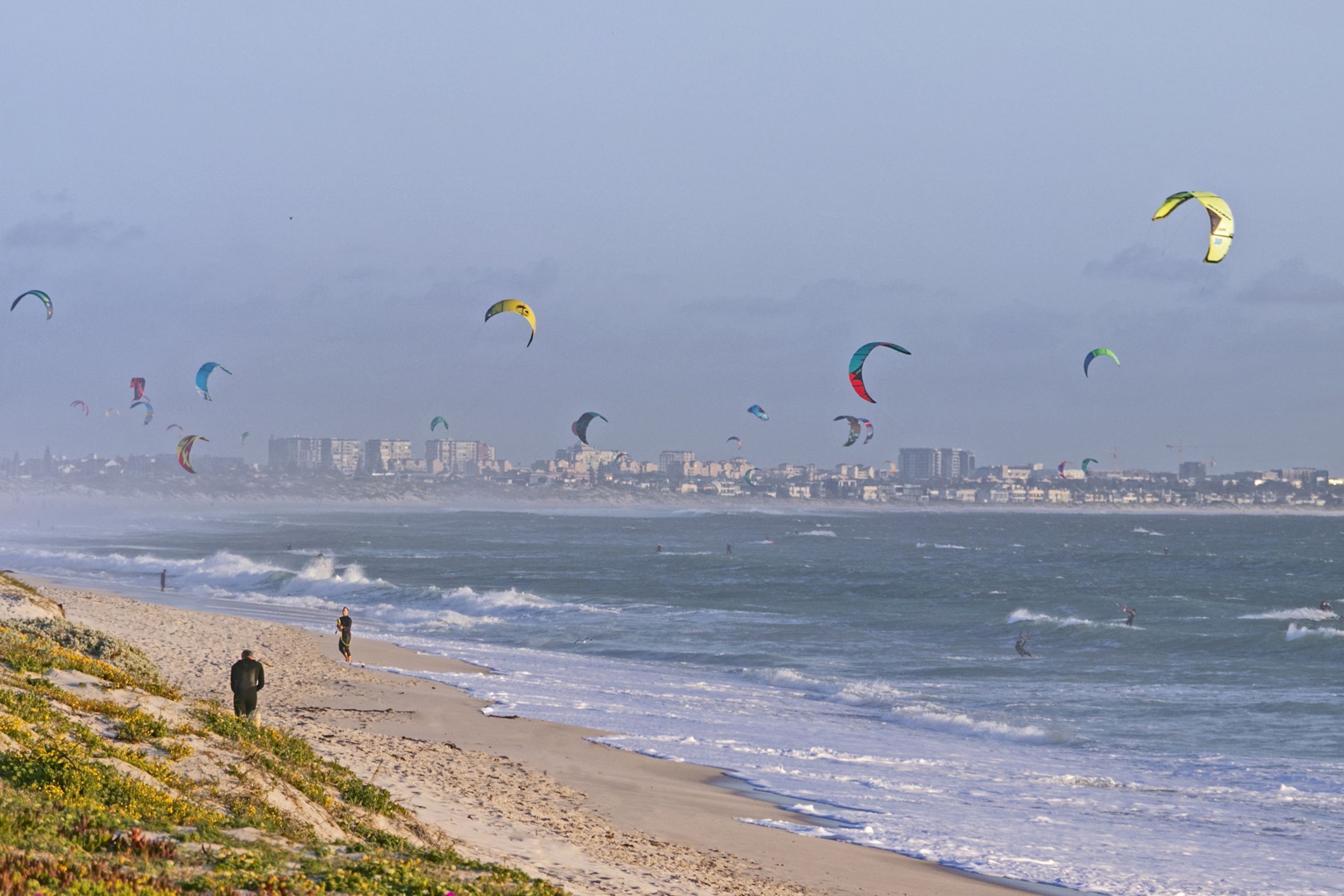 A beach with people and kites flying.