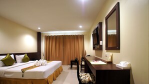 Habitación de hotel con cama, escritorio, sillas y televisor.