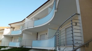 Un edificio de varios pisos con balcones, barandas y una escalera.