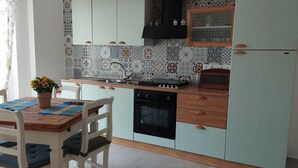 Una cocina compacta con salpicadero de azulejos, una estufa y un lavamanos.