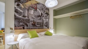 A modern bedroom with a large bed, green pillows, a headboard, a side table, a lamp, and a wall art piece. - Apartamento Interior, 1 Dormitorio 1 Baño (Malasaña)