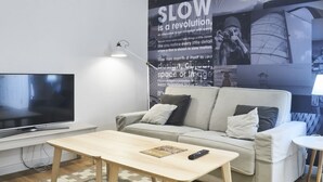 A modern living room with a flat-screen TV, a sofa, a coffee table, and a poster on the wall. - Apartamento Interior, 1 Dormitorio 1 Baño (Malasaña)