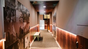 A hallway with a wooden floor, a bench, and a staircase in the background. - Apartamento Interior, 1 Dormitorio 1 Baño (Malasaña)