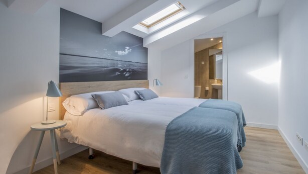 A modern bedroom with a large bed, skylight, and a view of the sea. - Apartamento Exterior Duplex 4 Dormitorios 3 Baños (Malasaña)