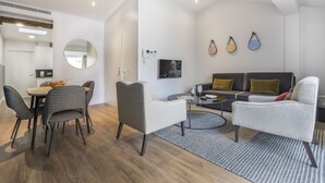 A modern living room with a sofa, chairs, a coffee table, and a dining area with a table and chairs.
