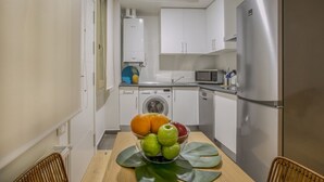 A compact kitchen with a washing machine, a refrigerator, and a microwave. - Apartamento Interior Duplex 1 Dormitorio 2 Baños (Malasaña)