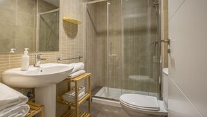 Ein modernes Badezimmer mit einer Duschkabine, einem Waschbecken mit Seifenspender und einer Toilette.