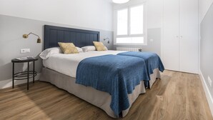 Una camera da letto con due letti, un piccolo comodino, una lampada e una finestra che lascia entrare luce naturale.