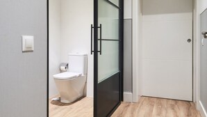 Un bagno moderno con un water, una porta in vetro e una porta bianca.