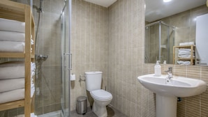 Een badkamer met een douchecabine van glas, een toilet, een wastafel en een handdoekhouder.