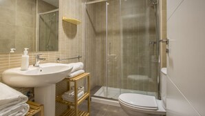 A modern bathroom with a glass-enclosed shower, a sink with a mirror, and a toilet. - Apartamento Interior Duplex 2 Dormitorios 2 Baños (Malasaña)
