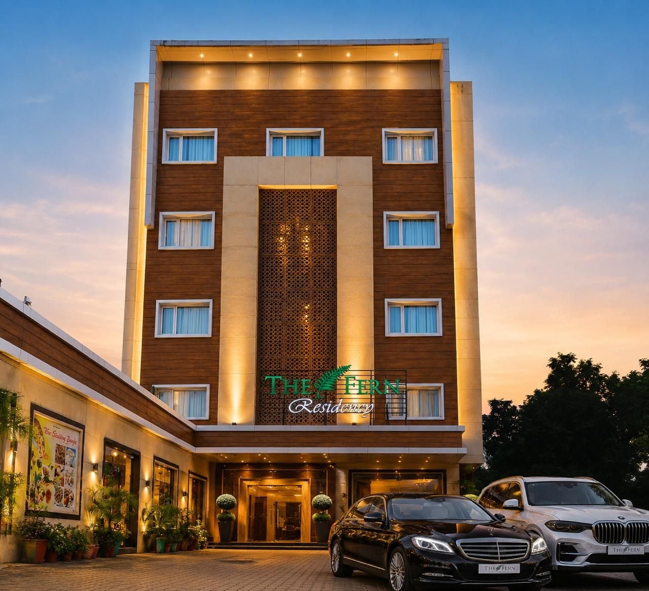 A multi-story hotel with a modern facade, a central entrance, and a sign indicating 'The Fern Residency.'