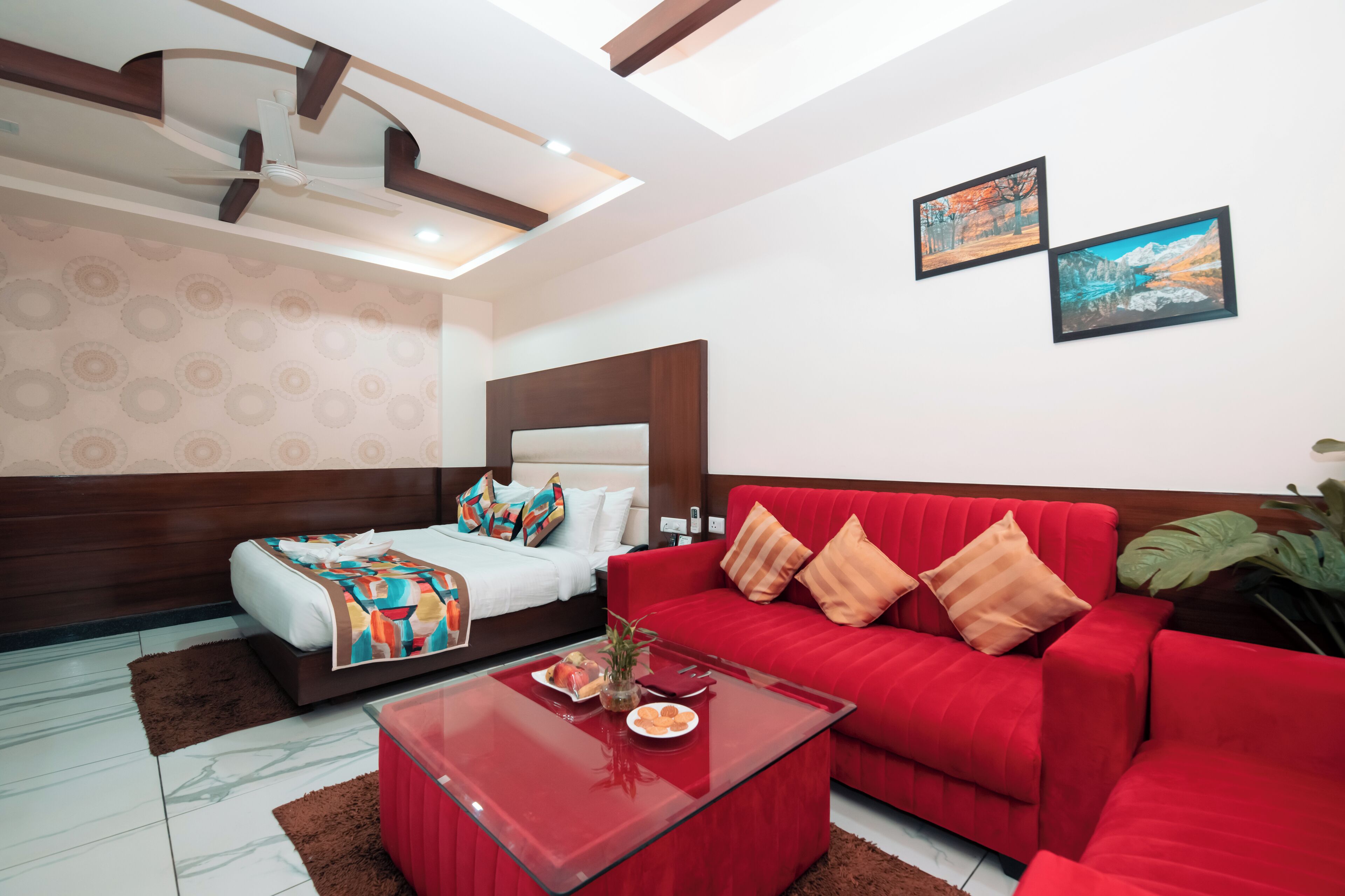 A modern hotel room with a bed, red sofa, and a glass coffee table.
