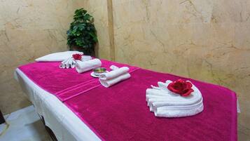 Relax in a serene spa treatment room with a massage table, potted plant, and soothing ambiance.
