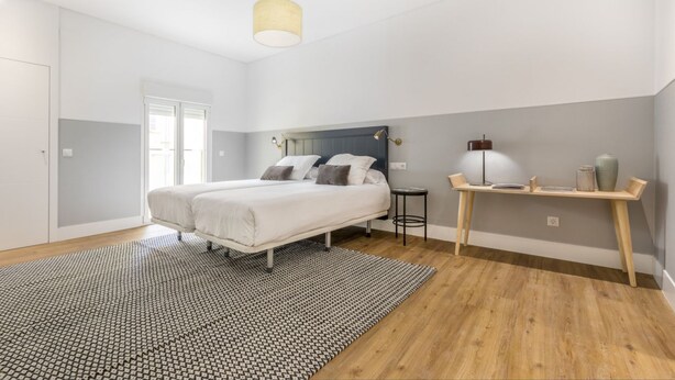 A bedroom with a bed, a bedside table, a lamp, and a window. - Apartamento Duplex 2 Dormitorios con Terraza (Madrid)
