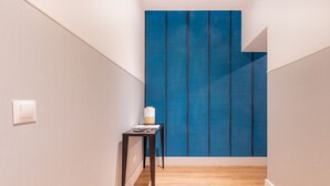 Un couloir étroit avec un plancher en bois, un mur d’accent bleu et une petite table avec une lampe.