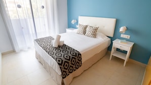Une chambre à coucher bien rangée, avec un lit, des tables de chevet et une fenêtre avec des rideaux.