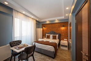 Ein modernes Schlafzimmer mit einer Ziegelwand, einem großen Bett, einem Esstisch mit Stühlen und einem Holzboden.