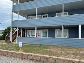 A multi-story building with a porch and a private parking sign. - Charming 2BR condo in Sunset Beach, perfect for 6 guests. Enjoy the patio! (Sunset Beach)