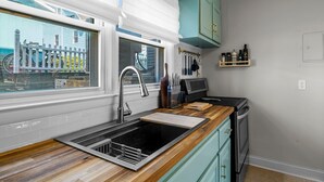 Una cocina moderna con pileta de acero inoxidable, encimera de madera y muebles color turquesa.