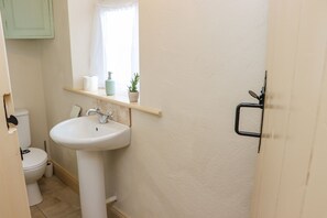 A bathroom with a white sink, toilet, and a window with a curtain.