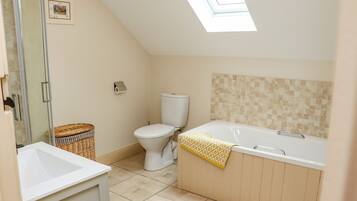 A bathroom with a skylight, a toilet, a bathtub, and a sink.