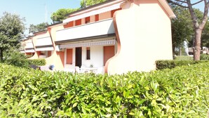 Ein Gebäude mit einer gewölbten Fassade, mehreren Balkonen und einem Garten davor.