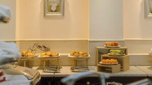 Habitación de hotel con un bufé de desayuno, que incluye bollería y frutas.