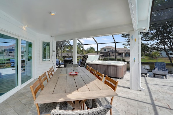 Relax in a serene outdoor space with a hot tub, comfortable seating areas, and a view of the surrounding neighborhood and water.