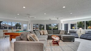 Ein geräumiges Wohnzimmer mit Billardtisch, einem Ecksofa und einem Couchtisch.