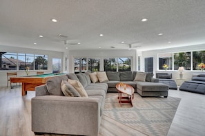Relax in a spacious living area with a large sectional sofa, pool table, and dining table, offering ample space for socializing and dining.