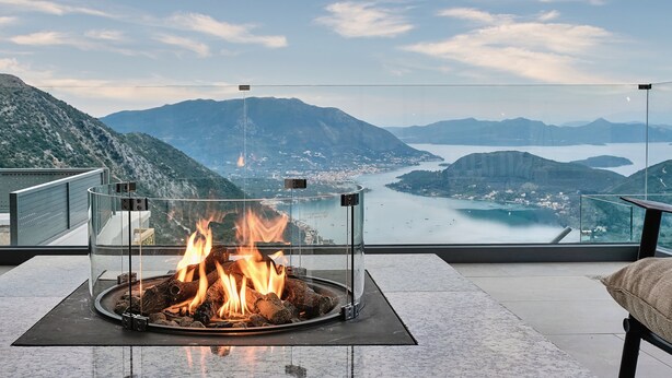 A fire pit with a clear glass enclosure, overlooking a mountainous landscape and a body of water. - Escape View Villa Lefkada (Fterno)
