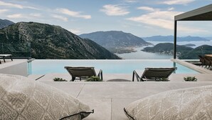 A poolside area with lounge chairs and a view of a mountainous landscape and a body of water. - Escape View Villa Lefkada (Fterno)