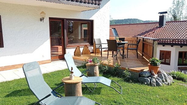 Eine Terrasse mit Gartenmöbeln, einer Holzdielenveranda und einer Steinmauer.