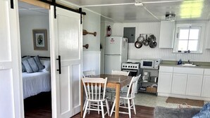 Un intérieur chaleureux comprenant un coin repas, un canapé, une cuisine et une chambre dotée d’une porte coulissante.