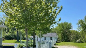 Une clôture blanche faite de piquets, un chemin de gravier et une pelouse agrémentée de bancs et d’un kiosque.