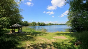 Ein Pavillon am See mit einer Bank und einem Picknicktisch.