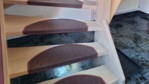 Eine Holztreppe mit Handlauf und Teppichstufen.