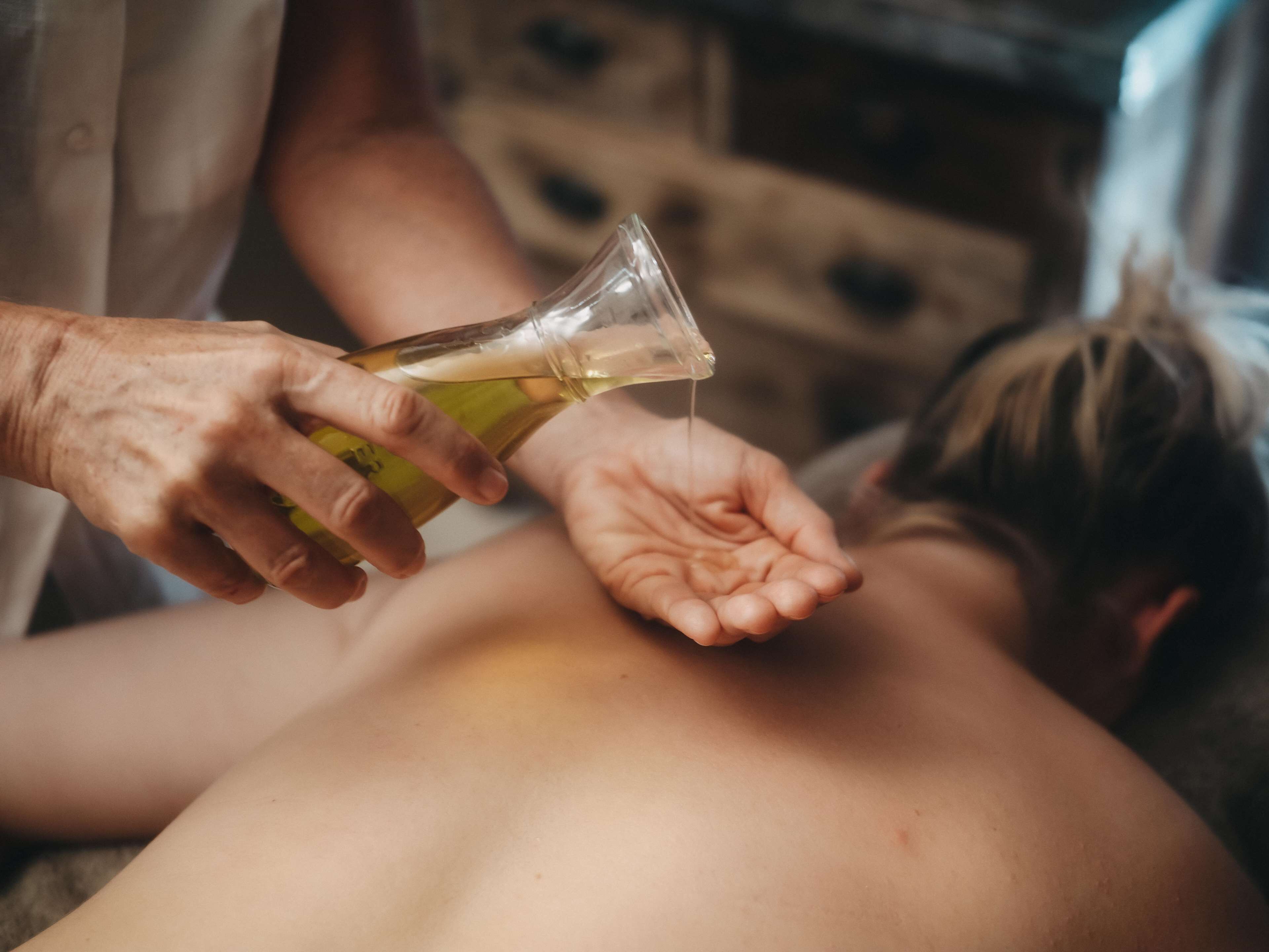 Una persona versa un liquido da una bottiglia nella mano di un'altra persona.