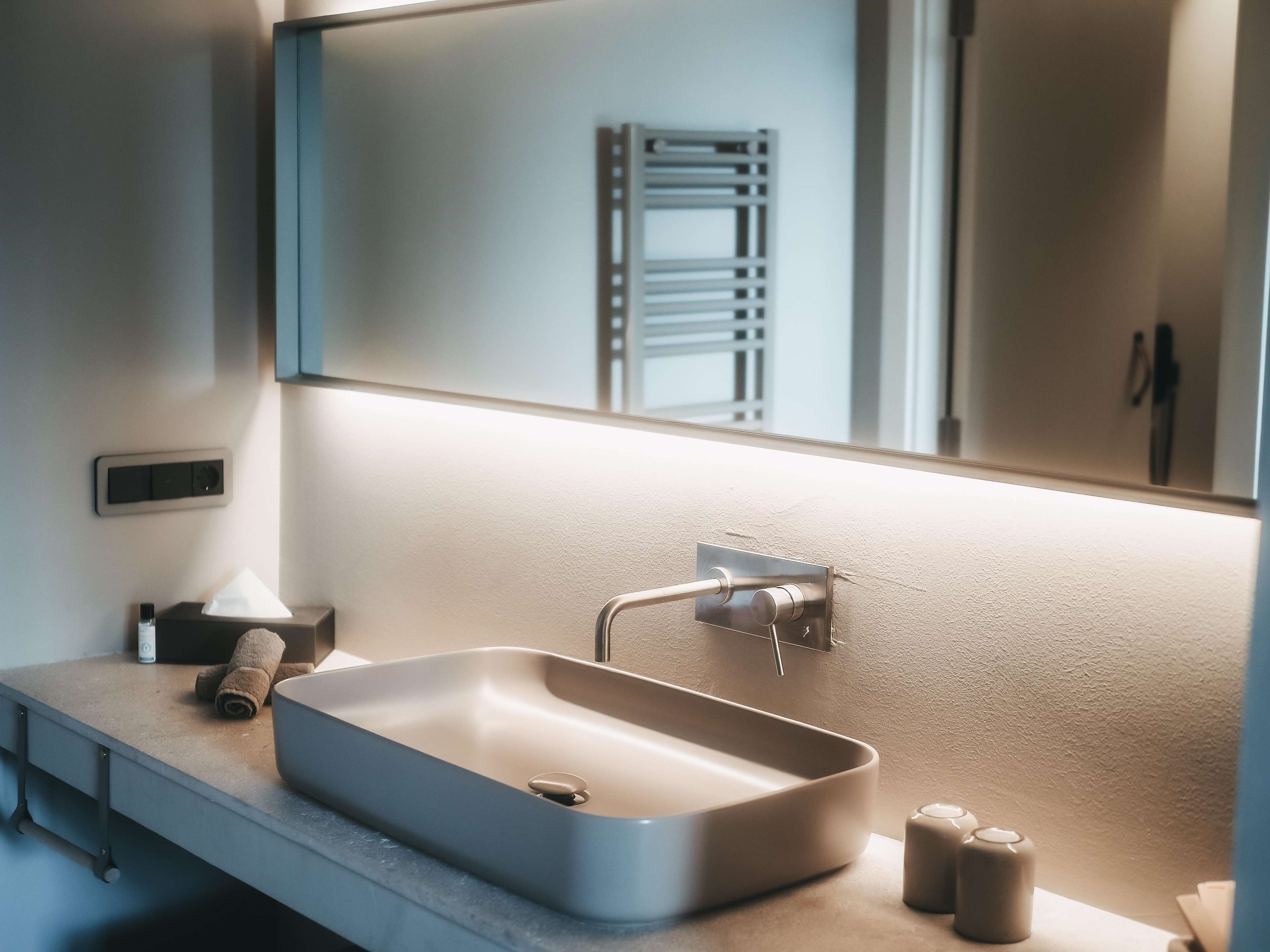 A modern bathroom with a rectangular sink, a towel, and a mirror.