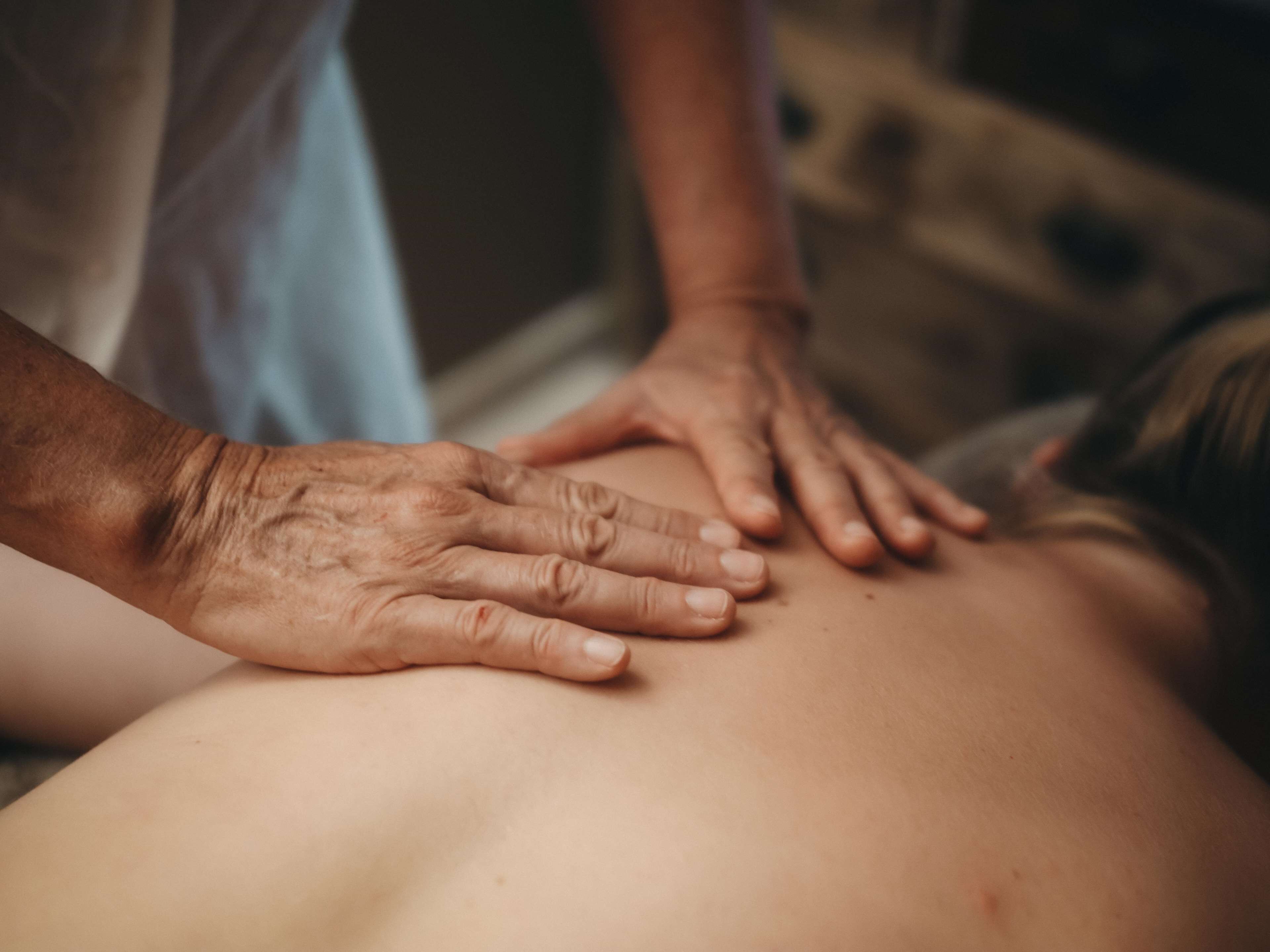 Gros plan sur des mains effectuant un massage sur le dos d’une personne.