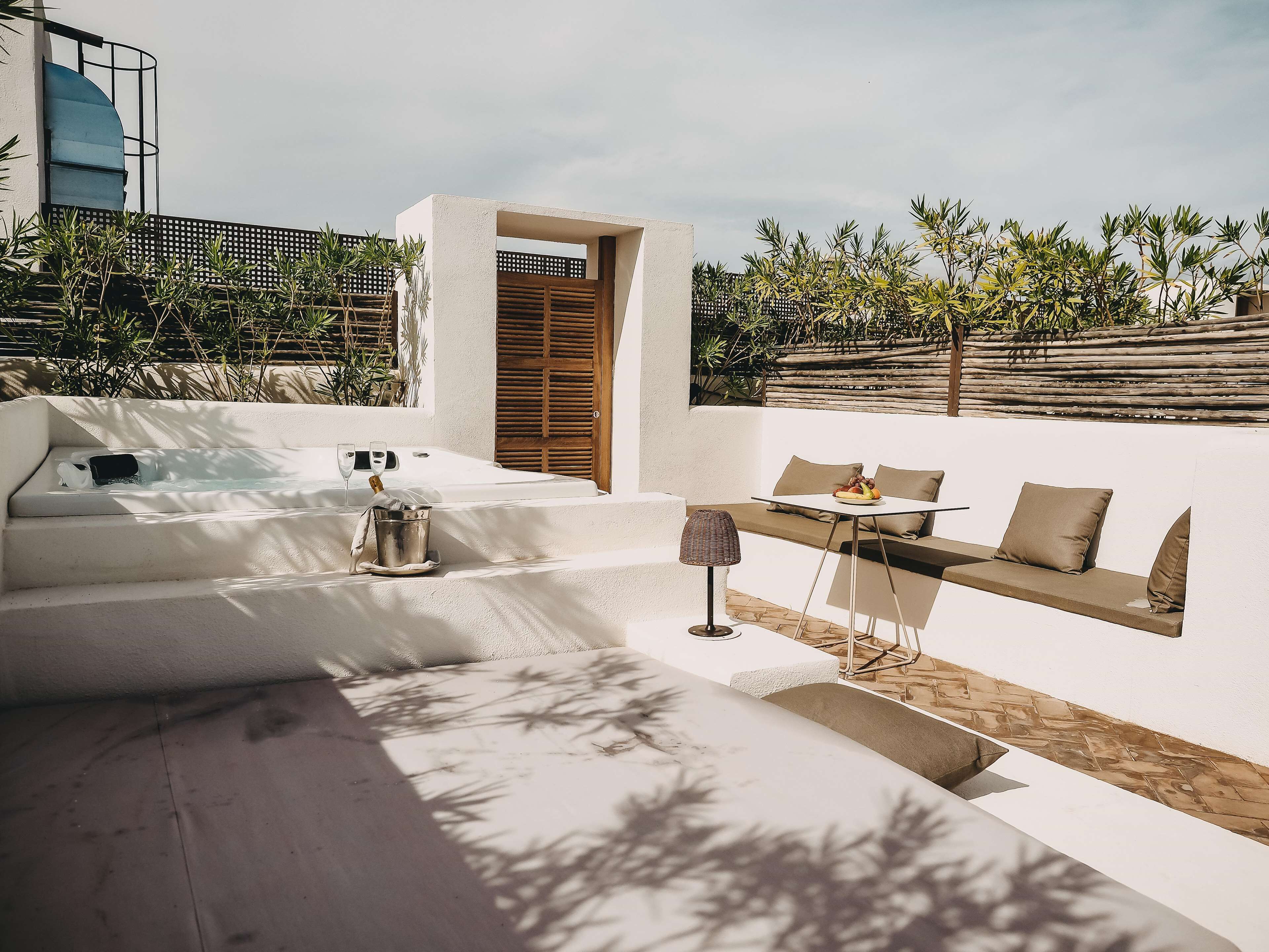 A modern outdoor seating area with a pool, a table with fruit, and a lounge chair.