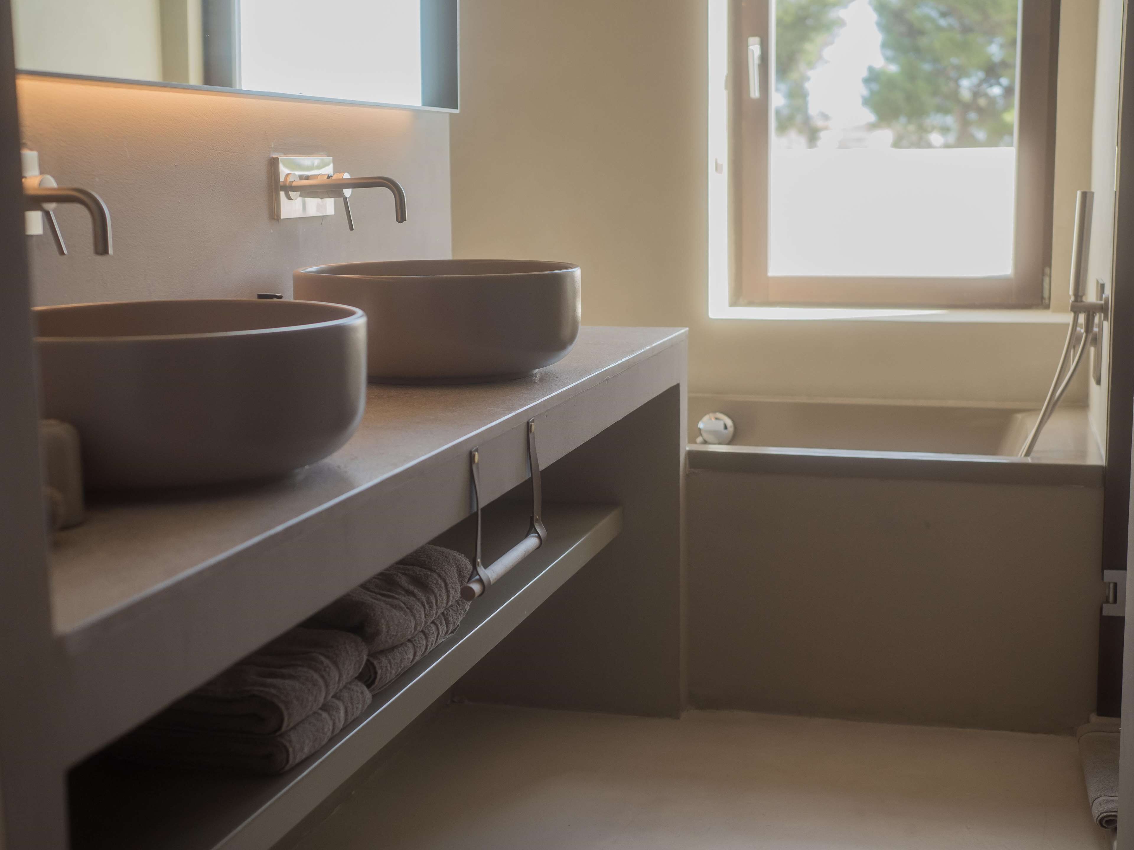 A bathroom with two vessel sinks, a towel rack, and a bathtub.
