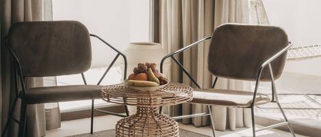 A room with two chairs, a woven table, and a fruit bowl.