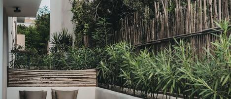 Un área de spa con un jacuzzi, valla de madera y exuberante vegetación.