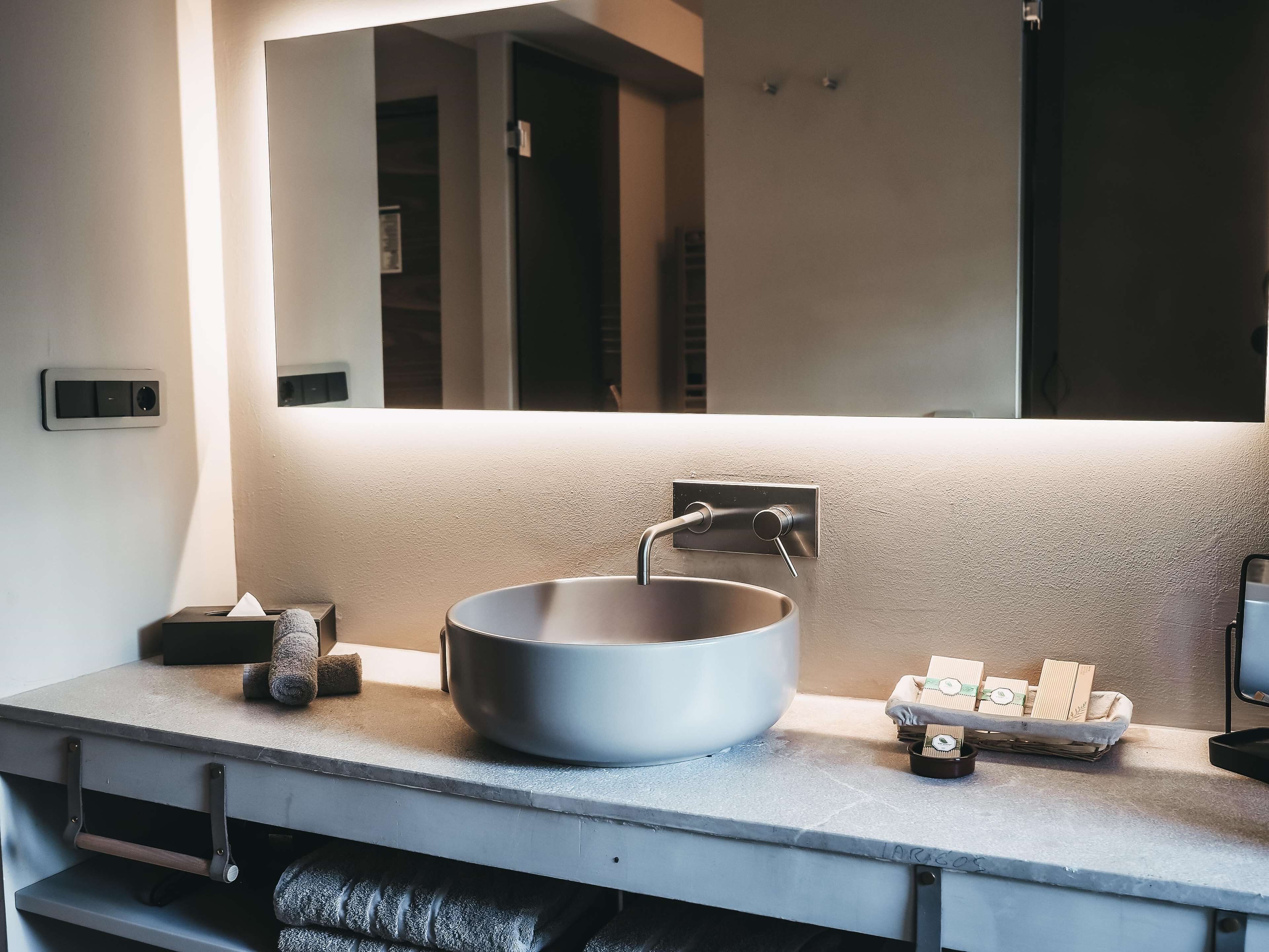 A modern bathroom with a large vessel sink, a towel rack, and a mirror above the sink.