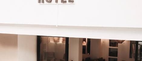 A hotel entrance with a modern design, featuring a glass door and a sign that reads "barefoot HOTEL".