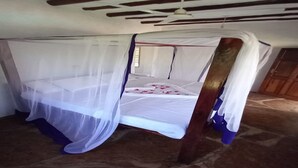 Ein Bett mit Baldachin, Holzbalken an der Decke und ein Steinfußboden.